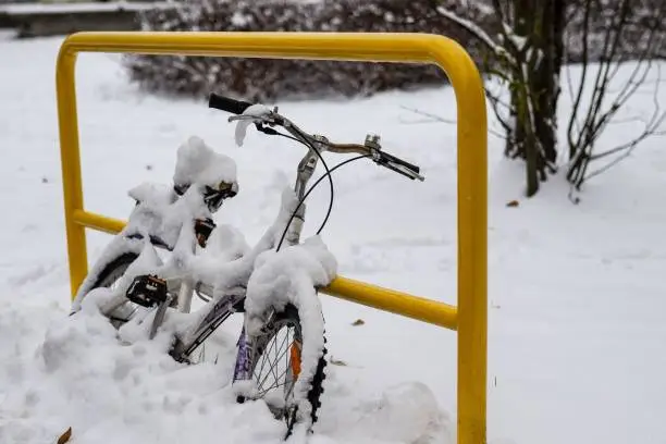 A winter scene featuring a bicycle partially covered by a blanket of fresh snow