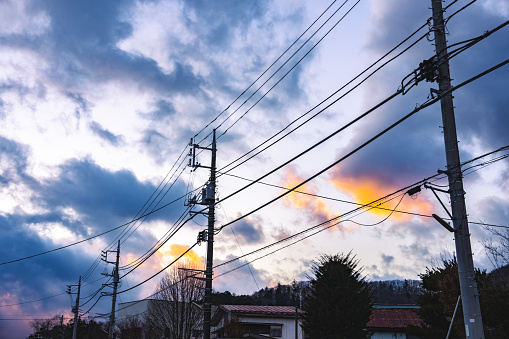 Electric high voltage tower with electric line at sunset