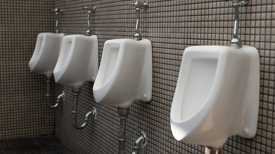 Toilet men's room. Row of outdoor urinals men public toilet, Closeup white urinals in men's bathroom, design of white ceramic urinals for men in toilet room. Empty advertisement in public toilet