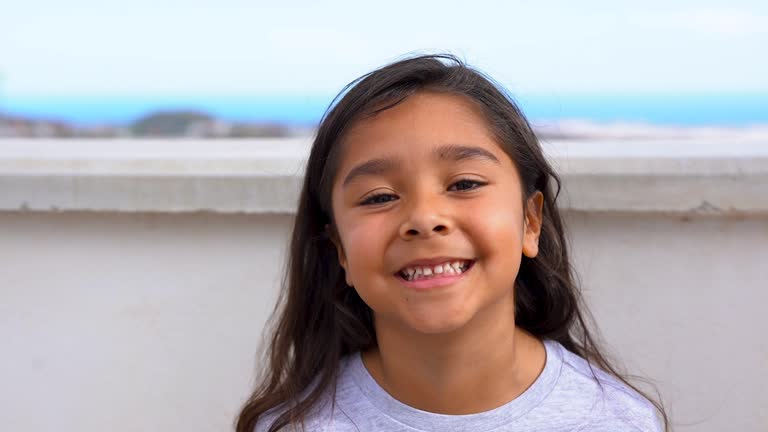 Happy latin girl smiling in front of camera outdoor - Preschool child having fun at house terrace