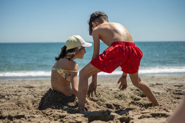 istock Siblings in the beach playing with sand 1487990475