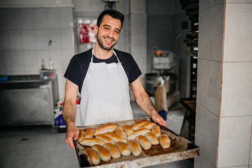 Baker taking bread out of oven