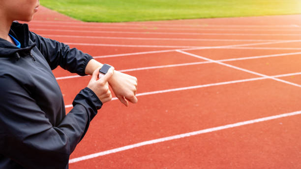istock Woman athlete runner standing on running tracks and using her digital wrist watch. 1487992148