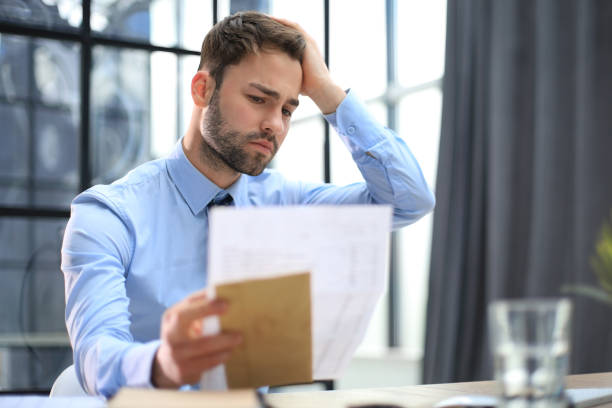 istock Sad entrepreneur reading a letter from envelope in a desktop at office. 1487992207