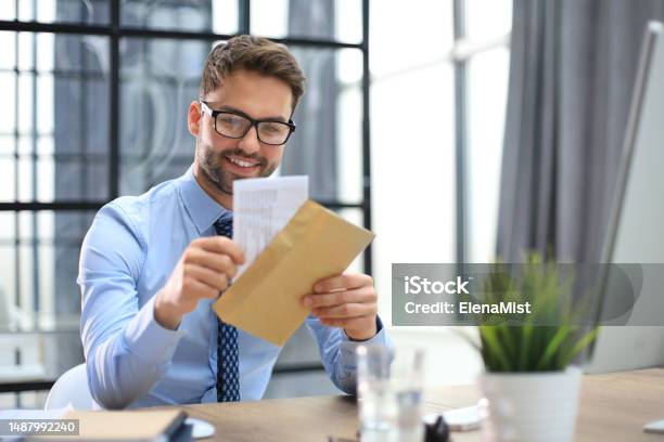 Jóképű Vállalkozó Aki Párnázott Borítékot Nyit Ki Egy Asztalon Az Irodában témájú stock fotó – Kép letöltése most