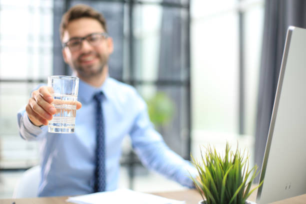 istock Handsome businessman using PC and drinking water in office area 1487992765