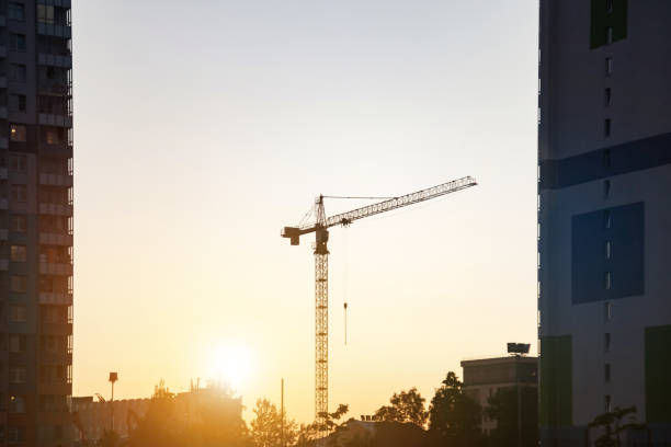 gru industriale silhouette sulla costruzione della casa di cantiere sullo sfondo del tramonto. gru industriale sul sito di creazione. concetto di costruzione e ristrutturazione di edifici. copiare lo spazio di testo dell'annuncio per il poster - plan urban scene city life construction foto e immagini stock