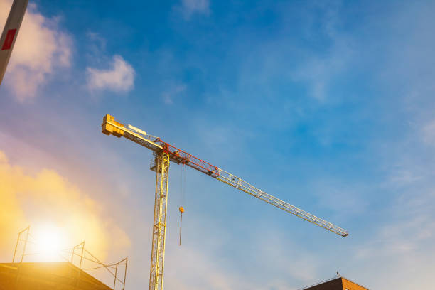 sfondo della gru gialla industriale sul cantiere al cielo blu con il sole. le gru industriali ospitano edifici sul cantiere. concetto di costruzione e ristrutturazione di edifici. copiare lo spazio di testo - plan urban scene city life construction foto e immagini stock