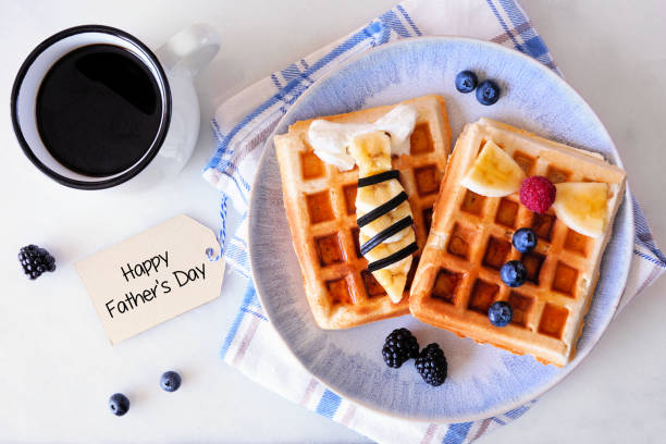 Fathers Day shirt waffles with necktie and bowtie with buttons. Above view over white marble. stock photo