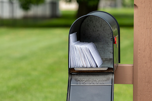 Mailbox full of letters and junk mail. Mail delivery, post office and postal service concept.