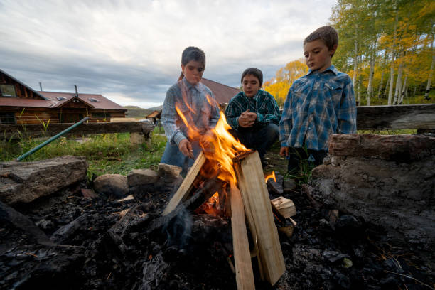 형제들은 콜로라도 주 텔루라이드에 있는 농장 목장에서 모닥불을 피우며 시골의 고요한 아름다움 속에서 소중한 추억을 만듭니다 - rocky mountains fire pit camping colorado 뉴스 사진 이미지
