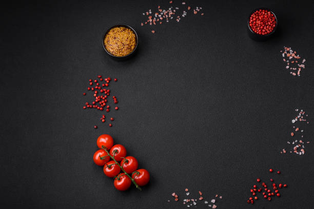 istock Empty black texture table, cherry tomatoes on a twig, spices, salt and herbs 1488002281