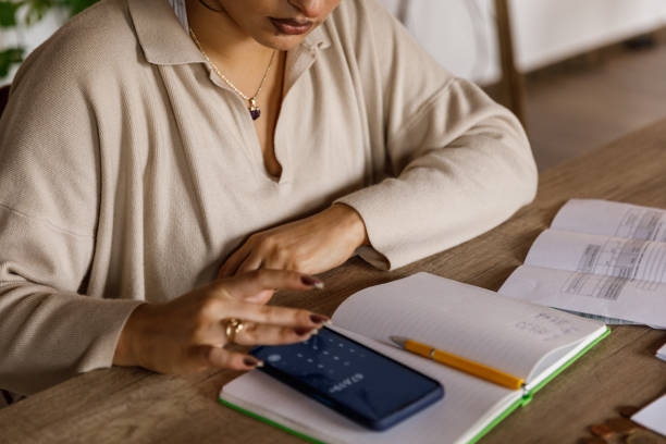 istock Young woman using a calculator app on her smart phone when sorting out finances at home 1488003418