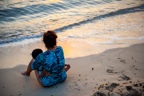 Mom and son enjoying the sunset on the beach