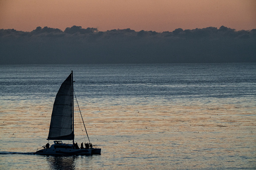 Lone Sailboat on Calm Pacific Ocean at Dusk with Low Clouds and Fog
