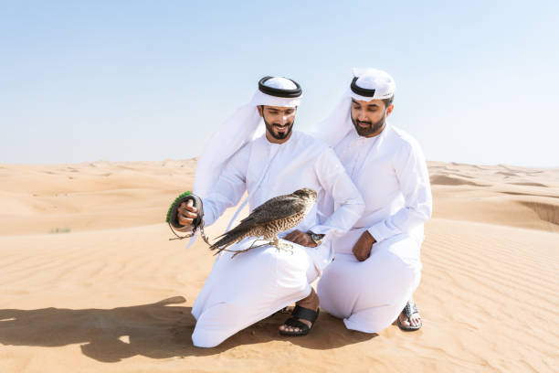 istock Two middle-eastern emirati men wearing arab kandura holding falcon in the desert 1488005607