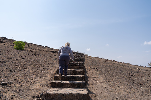 Woman hiker climbs the steep staircase to Observation Hill in Amboseli National Park Kenya Africa