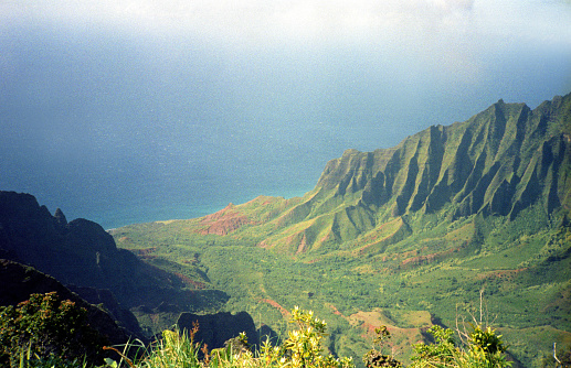A vintage 1980s film photograph aerial view of the lush green Hawaiian hills in the Honopu ridge valley in Kauai from a helicopter.