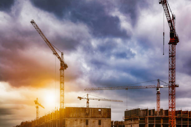 istock Construction site with cranes work at cloudy sky sunset backdrop. View of industrial crane on creation site. Concept of construction, industrialization and renovation of buildings. Copy ad text space 1488010122