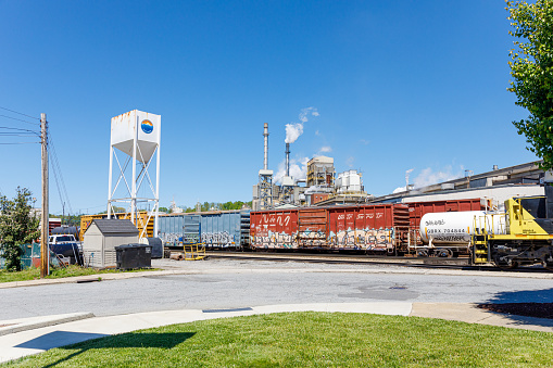 Canton, NC, USA-4 May 2023: Pactiv Evergreen papermill, with smokestacks, train cars in front. Blue Ridge Southern.