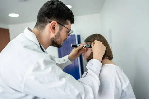 Doctor/otolaryngologist using an otoscope in a patient's ear at medical clinic