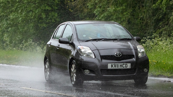 Stony Stratford,Bucks,UK - May 6th 2023. 2011 TOYOTA YARIS driving in the rain on a wet road