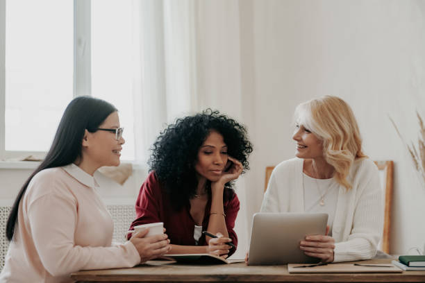 istock Three beautiful mature women using digital tablet while sitting at the desk together 1488021036