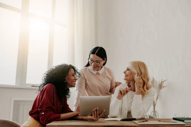 istock Three happy mature women using digital tablet while working in office together 1488021145