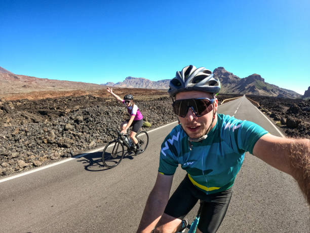 junges paar radfahrer machen ein selfie auf der straße im taide-nationalpark - cyclist cycling road women stock-fotos und bilder