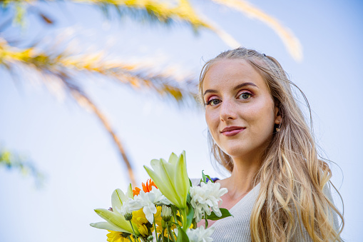 Portrait of a young Caucasian woman holding flowers with a confident expression