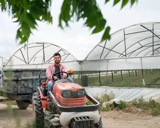 Photo of Portrait of young farmer man using tractor