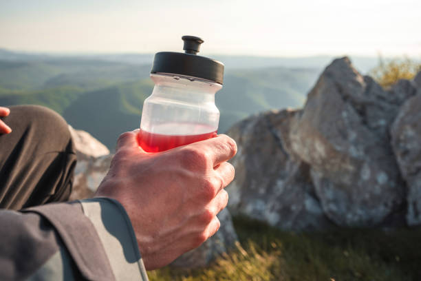 Cyclist resting and drinking water after a trail ride. He is sitting on his mountain bike and wearing a protective helmet. Concept of hydration, outdoor activity, and healthy lifestyle.