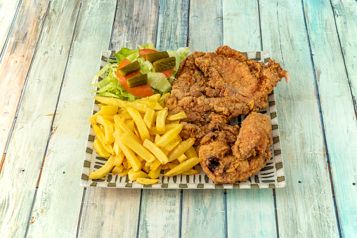 Broaster-style battered chicken pieces with French fries and salad of lettuce, tomato and pickled cucumbers