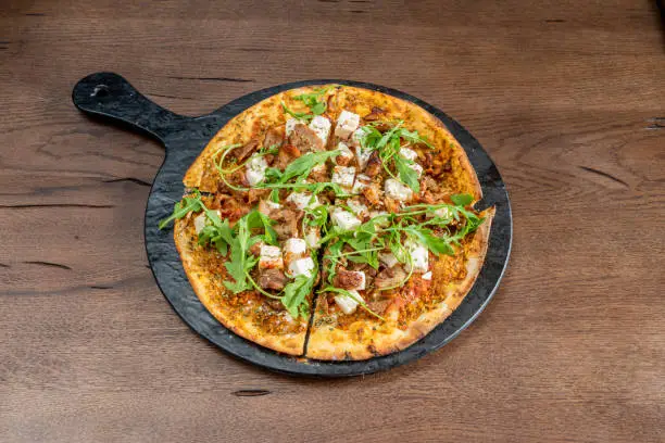 One-person sliced pizza with sliced meat, diced fresh cheese, tomato and arugula