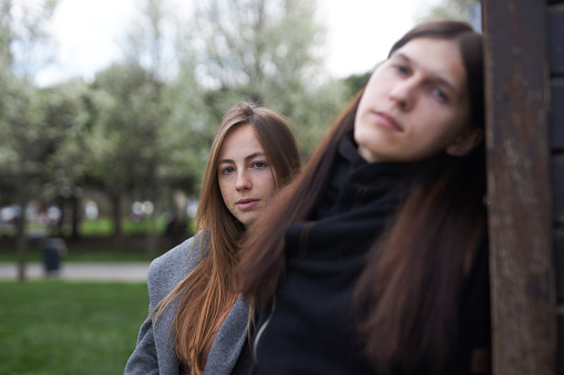 portrait of a young Russian couple with emotions and expressions like rock stars at a green park leaning on wooden wall