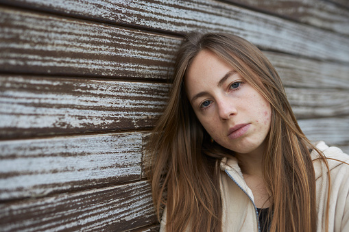 close-up portrait photo of a young Russian lady on a natural wood wall background in natural light outdoors