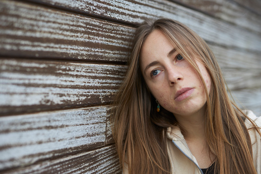 close-up portrait photo of a young Russian lady on a natural wood wall background in natural light outdoors