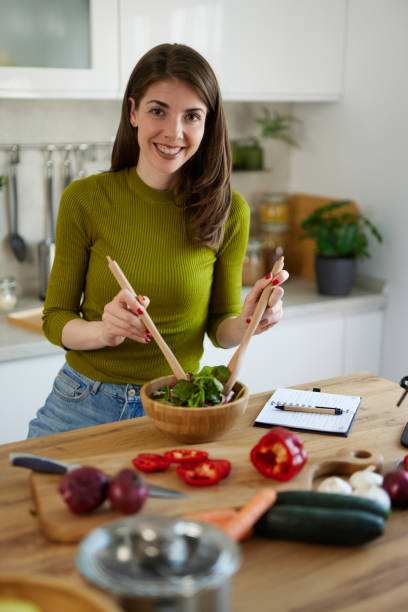 istock Young woman standing in the kitchen making a salad 1488041861