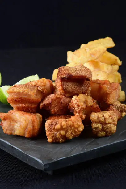 Photo of fried pork skin crackling pork pancetta pururuca typical brazilian food with lemon and french fries