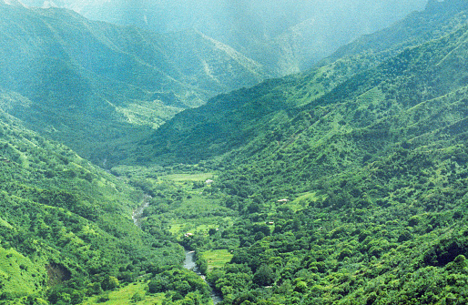 A vintage 1980s film photograph aerial view of the lush green Hawaiian hills in the Honopu ridge valley in Kauai from a helicopter.