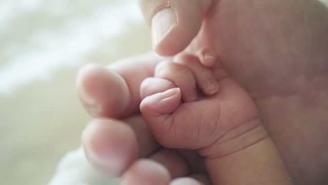 Mother hand holding and touching a little hand of baby newborn
