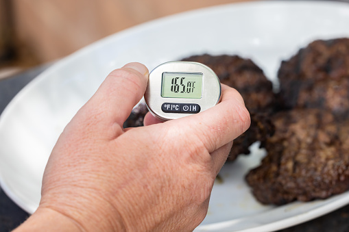 Using a digital food thermometer to check the temperature of cooked meat