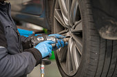 Changing winter tyres for summer tyres. car mechanic is tightening bolts on a wheel. automotive industry. Close-up of a wheel. car service, repair, maintenance concept. Garage workshop.
