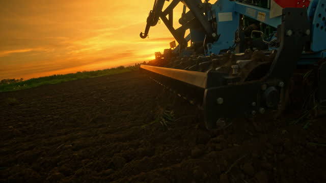 Close-up of Tractor Preparing Soil for Corn Planting at sunset