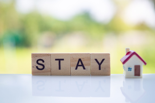The letters in the wooden blocks say stay at home. Controlling yourself at home is a preventive measure against the outbreak of the virus. Quid-19. Social distance and stay home and stay safe.
