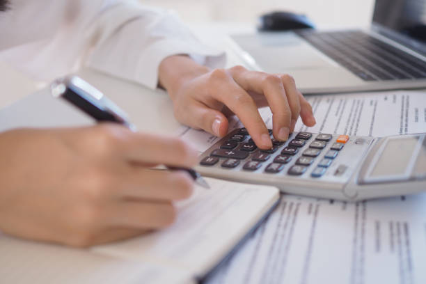 istock Asian businessmen work with calculators to calculate account information. In the office, work desks with documents and computers 1488067863