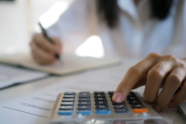 istock Asian businessmen work with calculators to calculate account information. In the office, work desks with documents and computers 1488067868