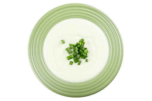 Cauliflower cream soup in a green plate isolated white background. File contains clipping path.