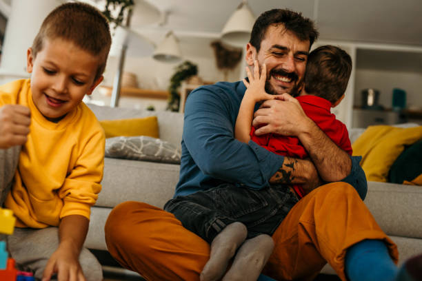 istock Father hugging and playing with his two sons at home. 1488072280