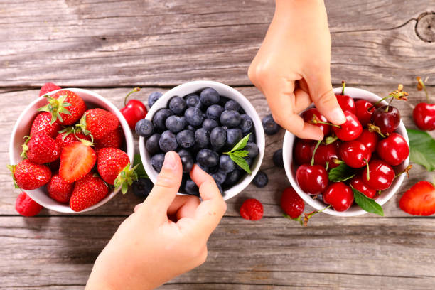 Closeup berries fruits at female hands. Blueberries, raspberries, strawberries, cherries and blackberries on the market. Gardening, agriculture, harvest and forest concept.